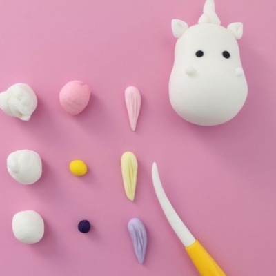 Conjunto de modelagem com massa colorida e figura de unicórnio em fundo rosa