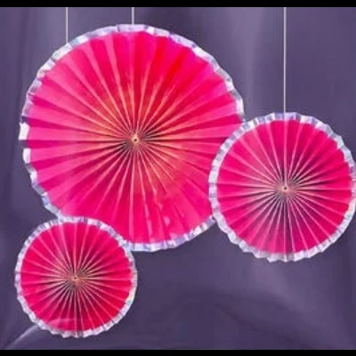 Leques decorativos em papel cor-de-rosa com borda branca pendurados.