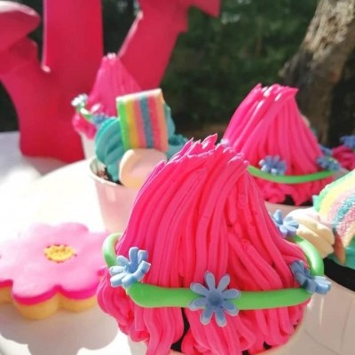 Cupcakes decorados com creme cor-de-rosa e pequenas flores azuis em ambiente exterior