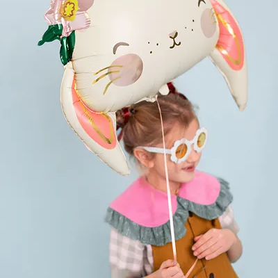 Balão metalizado em forma de coelho com flores, criança vestida colorida a segurá-lo