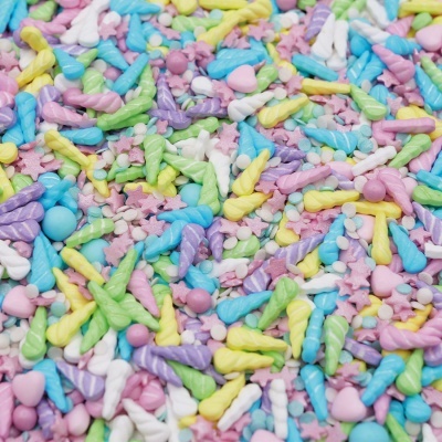 Confeites coloridos em forma de chifres de unicórnio, estrelas, corações e esferas em tons pastel