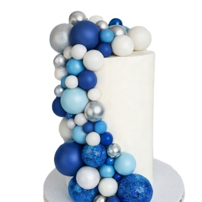 Bolo branco cilíndrico com decoração de bolas azuis, brancas e prateadas