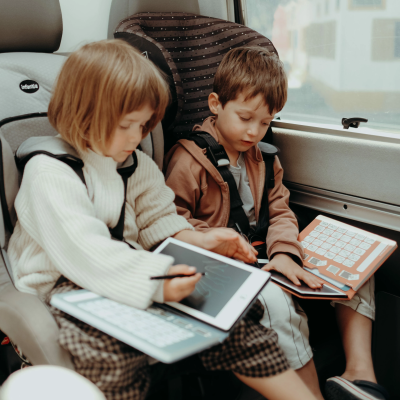 Crianças em cadeiras de automóvel com tablets e teclados integrados
