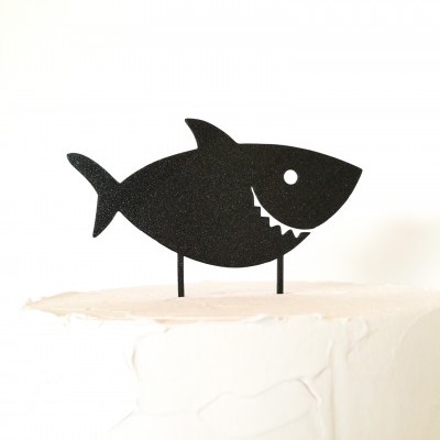 Topo de bolo em forma de tubarão preto sobre bolo branco