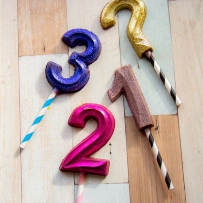 Velas coloridas em forma de números 3, 2, 1 e 7 sobre fundo de madeira