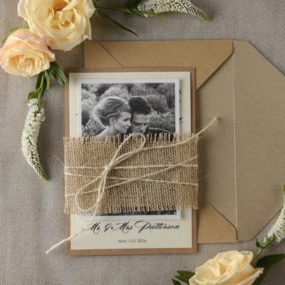 Convite de casamento com fotografia e tecido rústico, envelope castanho e flores à volta