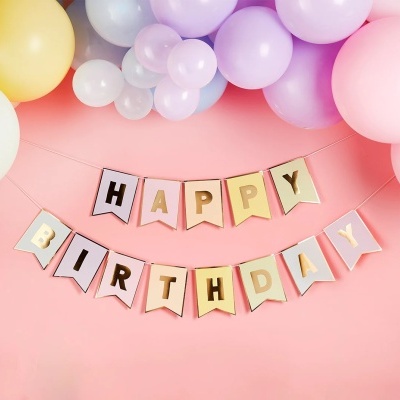 Faixas decorativas HAPPY BIRTHDAY com balões coloridos pastel numa parede rosa.