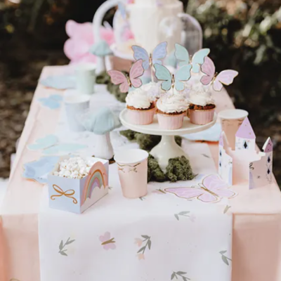 Mesa decorada com cupcakes, pipocas e castelo de papel para festa com tema de borboletas.