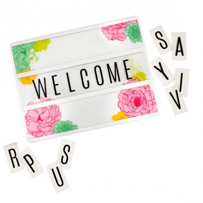 Placa branca decorada com flores e letras pretas a formar a palavra WELCOME
