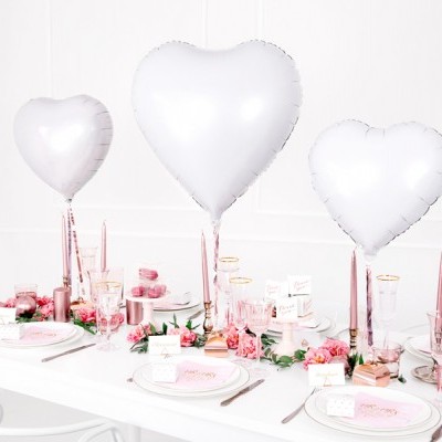 Mesa decorada com balões prateados em forma de coração e acessórios cor-de-rosa