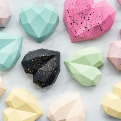 Corações de chocolate coloridos em formato geométrico sobre fundo branco