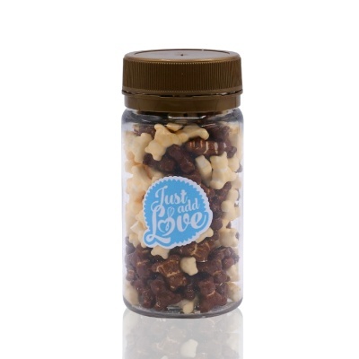 Frasco transparente com tampa castanha cheio de biscoitos em forma de ossos castanhos e creme e etiqueta azul com o texto Just add Love