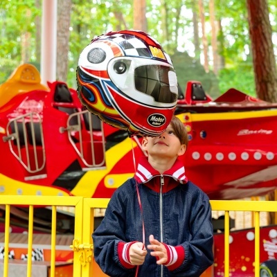 Balão com forma de capacete de mota que criança segura em parque de diversões