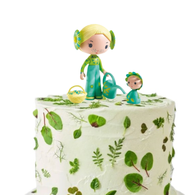 Bolo decorado com folhas verdes e figuras de bonecos no topo