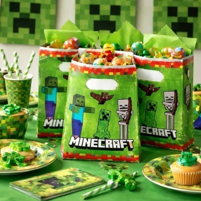 Sacolas de festa temáticas Minecraft com personagens e texto, numa mesa com decoração e comida temática.