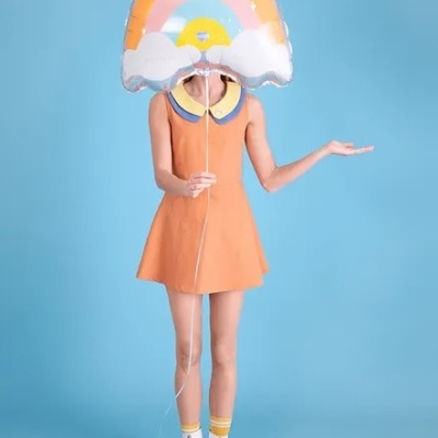 Pessoa com vestido laranja e balão em forma de arco-íris