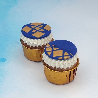 Dois cupcakes com cobertura branca e disco azul com padrão dourado, em forminhas douradas.
