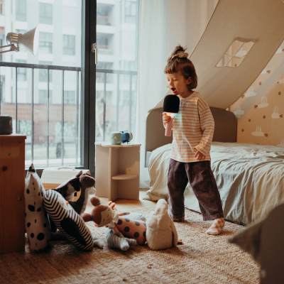 Criança a cantar num quarto com decoração e brinquedos