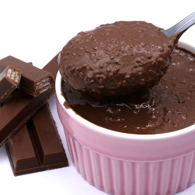 Creme de chocolate espesso numa taça rosa com colher e barras de chocolate de leite