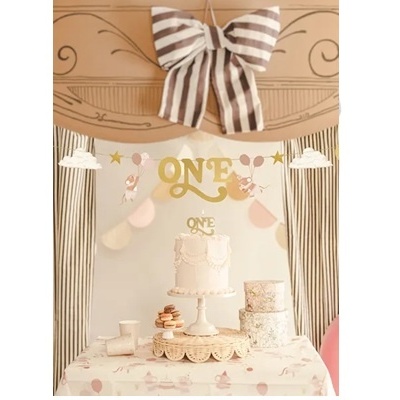 Decoração de festa de aniversário com bolo branco, laço listrado e cortinas listradas.