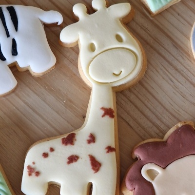 Biscoito girafa decorado em glacê branco e castanho sobre superfície de madeira clara