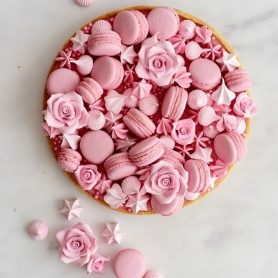 Tarte redonda com decoração rosa de macarons, flores de açúcar e merengues