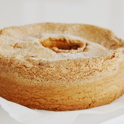 Bolo redondo bege claro com buraco no centro em papel branco