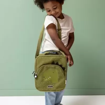 Criança com bolsa de ombro verde com ilustração de dinossauro