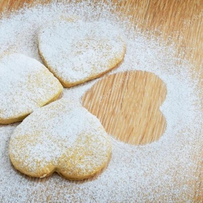 Bolachas em forma de coração polvilhadas com açúcar em pó numa tábua de madeira