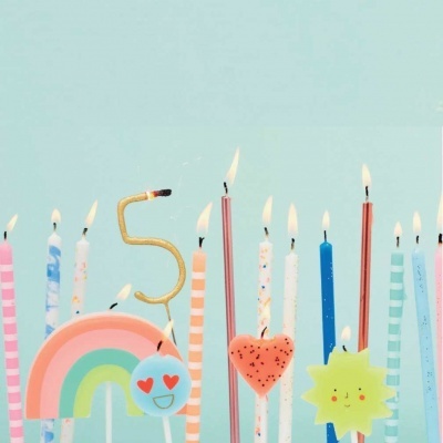 Velas de aniversário coloridas e decorativas acesas sobre fundo azul claro
