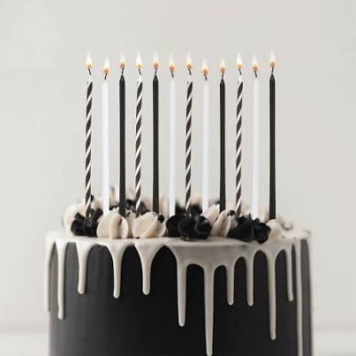 Bolo preto com cobertura branca e velas pretas e brancas acesas