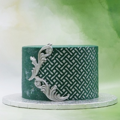 Bolo verde escuro com padrão geométrico e detalhes prateados em relevo