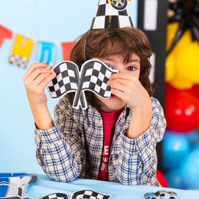 Criança com chapéu de festa quadriculado e segurando bandeiras quadriculadas pretas e brancas