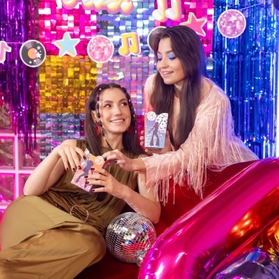 Duas mulheres jovens em festa com caixas decorativas e balões coloridos