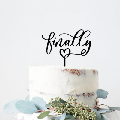 Bolo com creme branco e decoração de folhas verdes com topo em texto preto 'finally'.