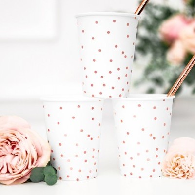 Três copos de papel brancos com pontos rosa dourado e flores rosas ao redor