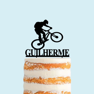 Topo de bolo de ciclista com texto GUILHERME num bolo de camadas