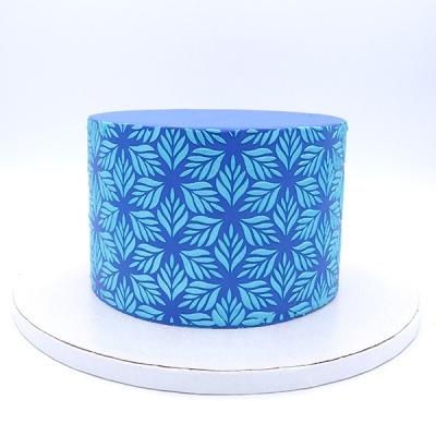 Caixa cilíndrica azul com padrão de folhas colocada em base branca