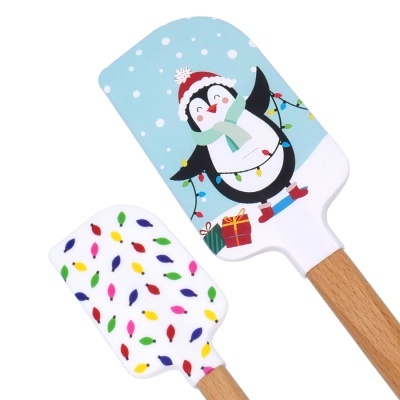 Espátulas de cozinha em madeira e silicone com desenhos de Natal, Fundo azul com pinguim e luzes coloridas.