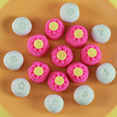 Doces redondos coloridos decorados com flores e desenhos simples em prato laranja