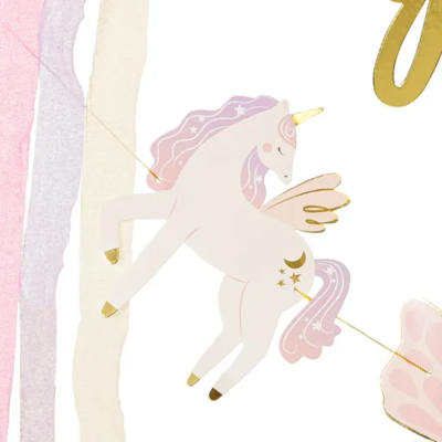 Móbile com unicórnio branco e rosa pendurado com faixas coloridas ao fundo