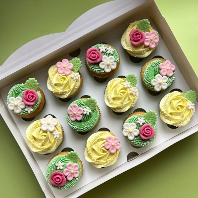 Doze cupcakes decorados com flores de glacé em caixa branca