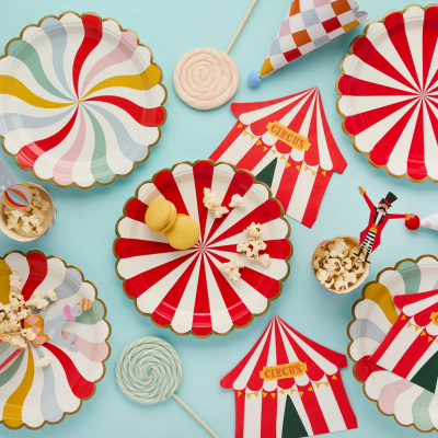 Mesas de festa com pratos decorativos, pipocas, pirulitos e elementos de circo coloridos
