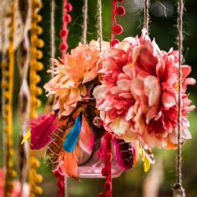 Frascos de vidro suspensos com flores artificiais e penas coloridas