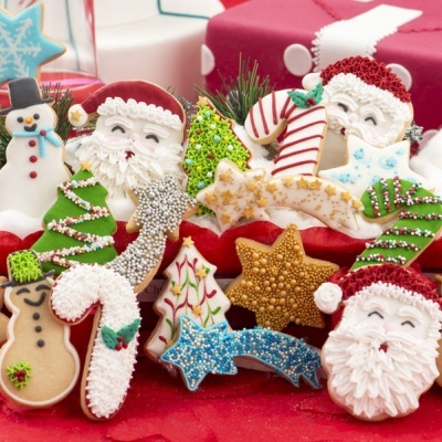 Biscoitos natalícios decorados com glacê e açúcar colorido, incluindo figuras de Papai Noel, árvores de Natal, estrela e boneco de neve.