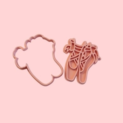 Cortadores de biscoitos cor de rosa em formas relacionadas com sapatilhas de balé sobre fundo rosa.