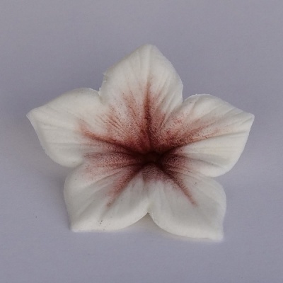 Flor artificial branca com padrão avermelhado no centro sobre fundo cinza