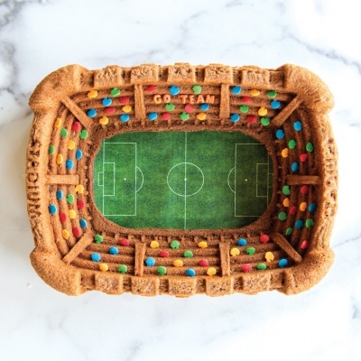 Biscoito em forma de estádio de futebol com campo verde e confeitos coloridos
