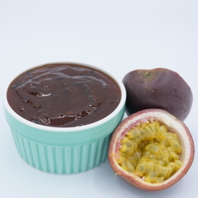 Ramequim com creme castanho escuro e maracujás, um cortado ao meio