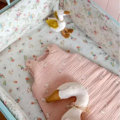 Berço com saco de dormir rosa estampado e brinquedos de ganso de pelúcia